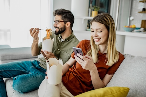man and woman eating on a couch