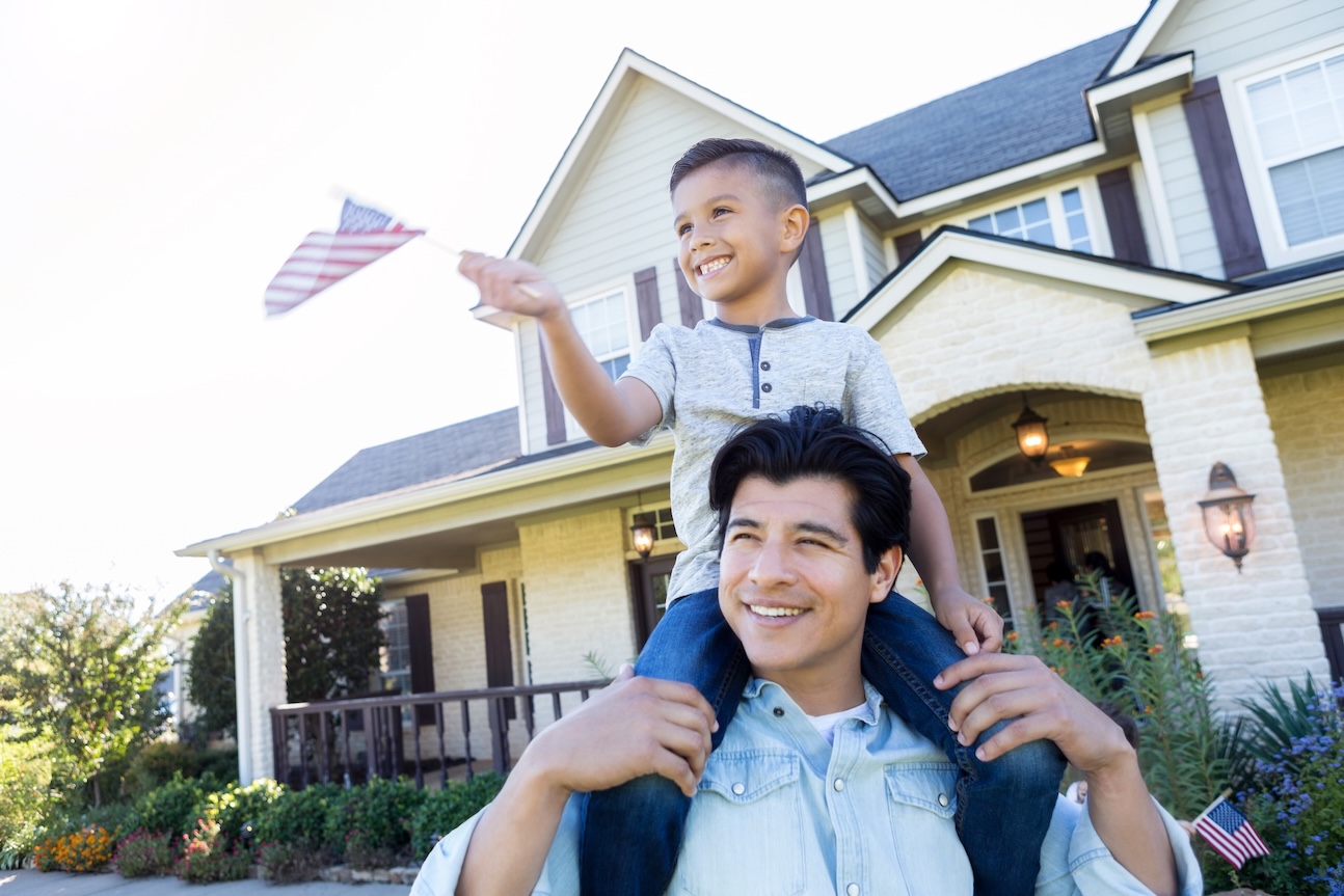 boy waving US flag on man's shoulders